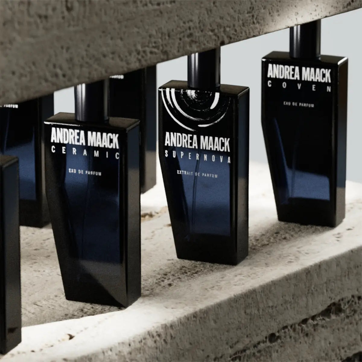 Andrea Maack Parfums - Supernova schwarzer Flakon mit weißer Schrift und geometrischem Design auf rauem Betonhintergrund