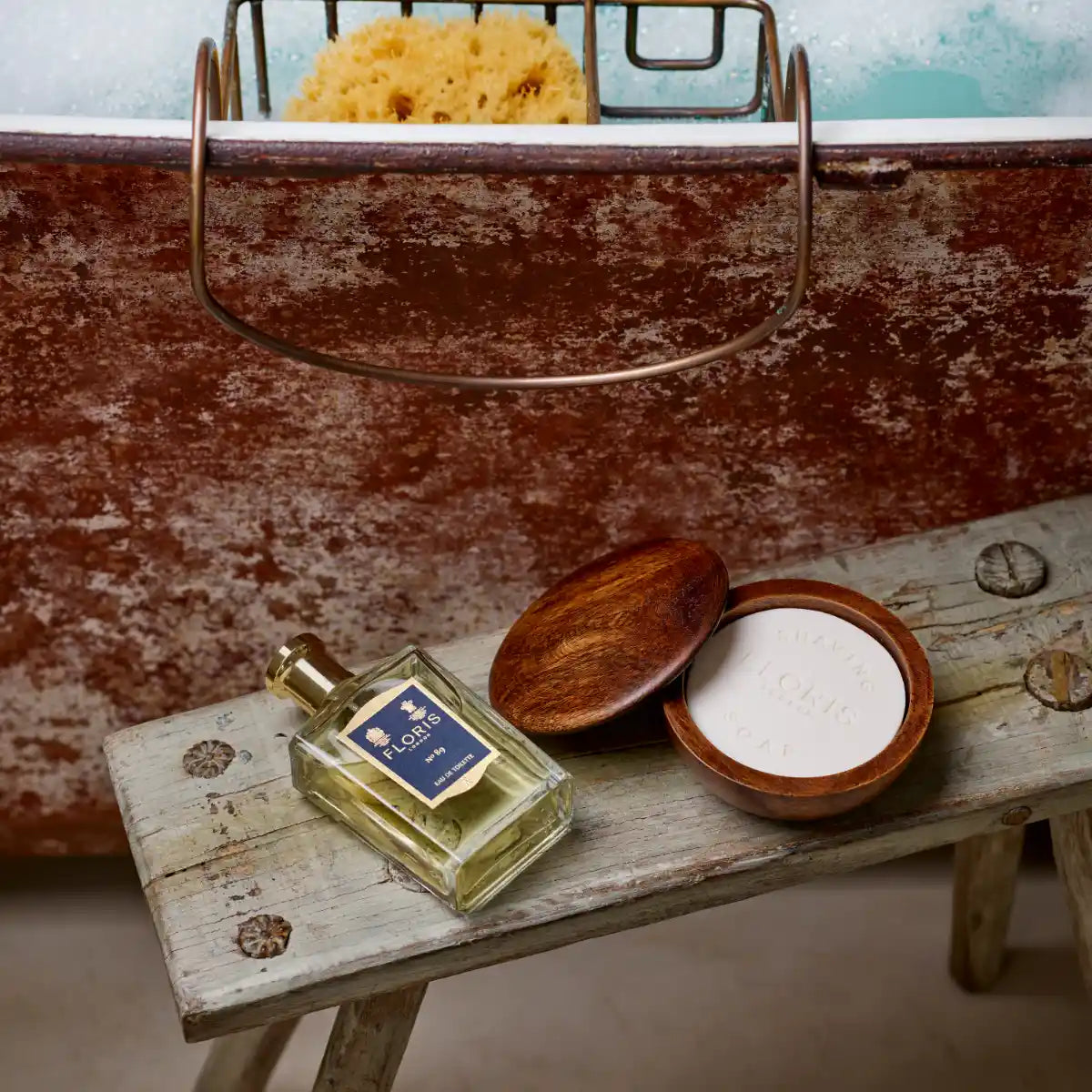 Floris - No. 89 Flakon mit dunkelblauem Etikett und goldfarbenem Verschluss auf altem Holzhocker vor Metallbadewanne