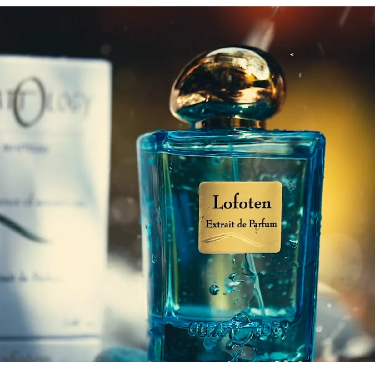 Olfattology - Lofoten Parfumflakon in transparentem Blau mit goldfarbenem Verschluss vor unscharfem Hintergrund