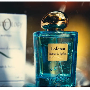 Olfattology - Lofoten Parfumflakon in transparentem Blau mit goldfarbenem Verschluss vor unscharfem Hintergrund