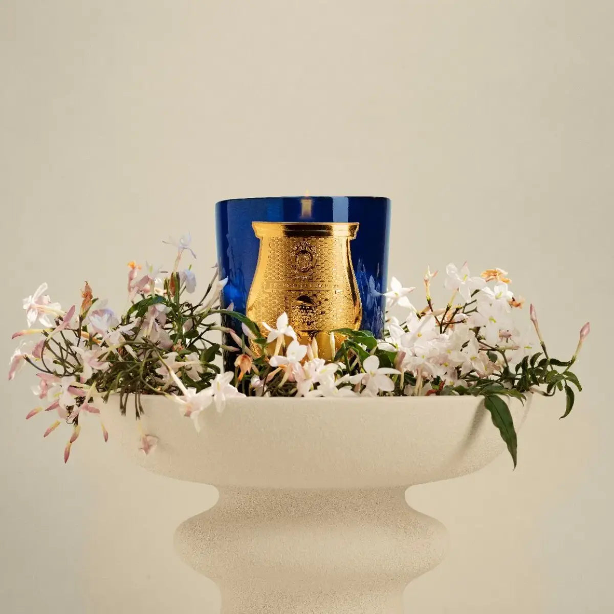 Trudon - Les Belles Matières - Maduraï - Duftkerze im dunkelblauen Glas mit goldenem Emblem und Jasminblütenarrangement