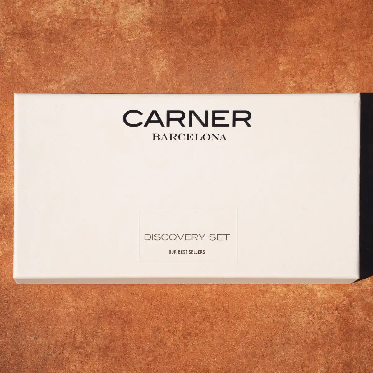 Carner Barcelona - Our Bestsellers Discovery Set elegante weiße Schachtel mit Logo auf warmem Terrakottahintergrund
