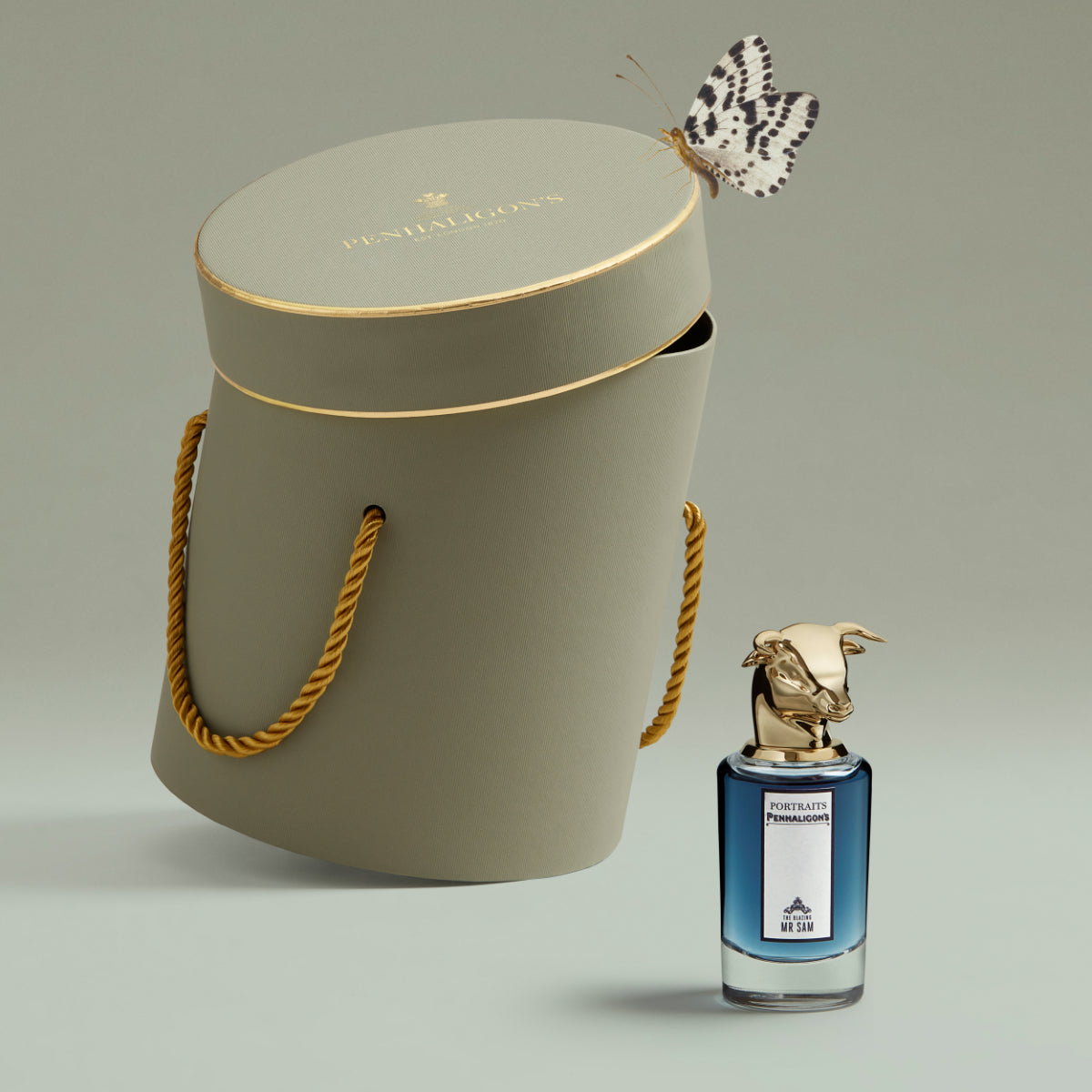 Penhaligon's - Portraits - The Blazing Mister Sam Flakon mit goldenem Stierkopf vor edler Geschenkbox und Schmetterling