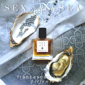 Francesca Bianchi - Sex and the Sea Parfumflakon mit bernsteinfarbener Flüssigkeit, umgeben von Muscheln und Perlen