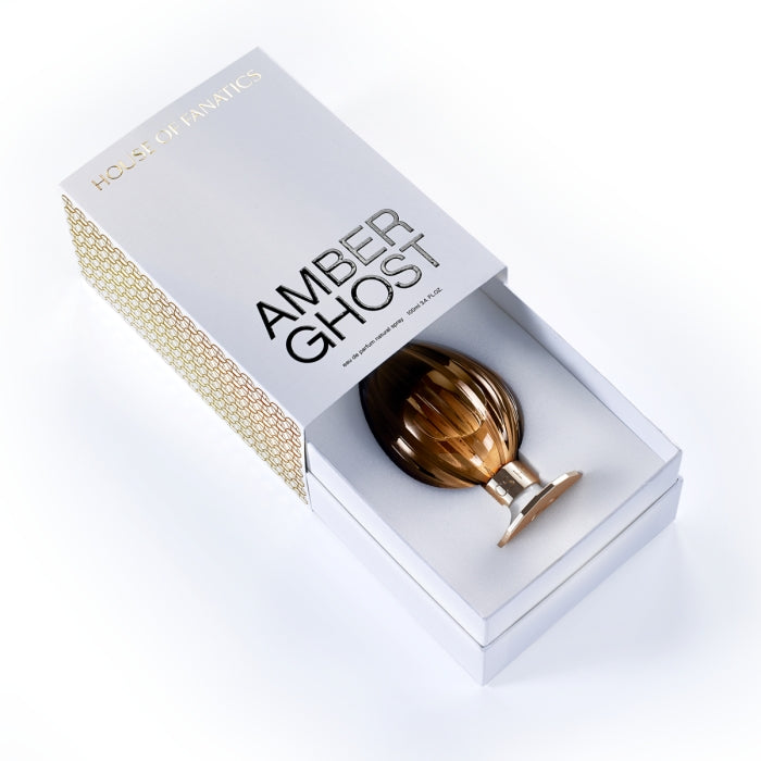 House of Fanatics - Amber Ghost zeigt eleganten bernsteinfarbenen Flakon mit goldfarbenem Sockel in edler Geschenkbox