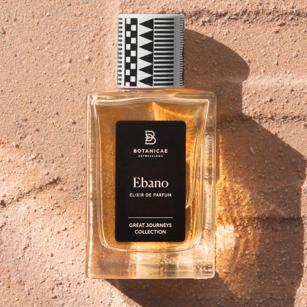 Botanicae - Ébano Parfumflakon mit schwarzem Etikett und geometrischem schwarz-weißem Verschluss auf sandigem Untergrund