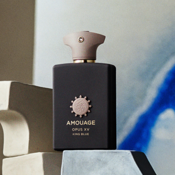Amouage - Library Collection - Opus XV - King Blue zeigt mattschwarzen Flakon mit beigem Verschluss vor abstraktem Hintergrund