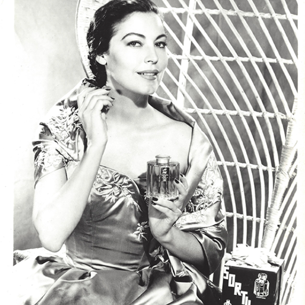 Le Galion - L'Astre Werbefoto mit eleganter Frau in glänzendem Kleid und Parfumflakon vor Vintage-Kulisse