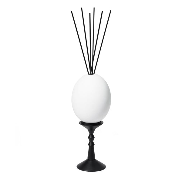 Trudon - L’Œuf Diffusor - Cyrnos mit weißem Ei auf schwarzem Ständer und schwarzen Diffusstäbchen vor weißem Hintergrund