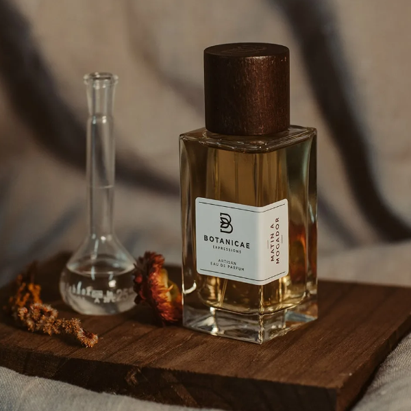 Botanicae - Matin à Mogador Parfumflakon mit dunklem Holzverschluss auf rustikalem Holzbrett vor unscharfem Hintergrund