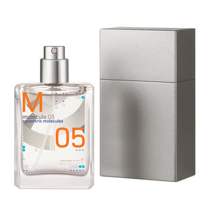 Escentric Molecules - Molecule 05 Travel Spray transparentes Flakon mit orangen Details neben silberner Reisehülle vor weißem Hintergrund