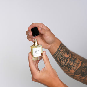 Bodé Studios - Satin Cache Parfumflakon mit goldenem Zerstäuber und schwarzem Deckel in Händen vor hellem Hintergrund